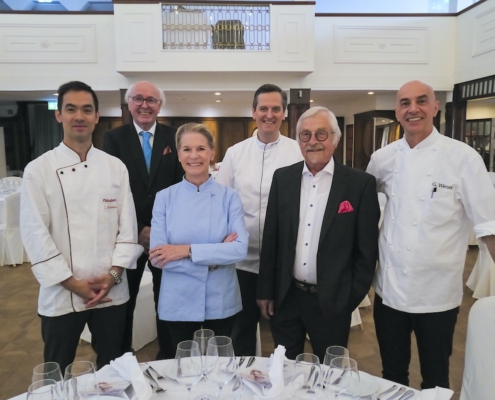 Vier bekannte Köche und zwei Herren in Anzügen lächeln in einem großen Saal in die Kamera. Sie sind das Team zur Eröffnung des 38. Schleswig-Holstein Gourmet Festivals in Pinneberg bei Hamburg.